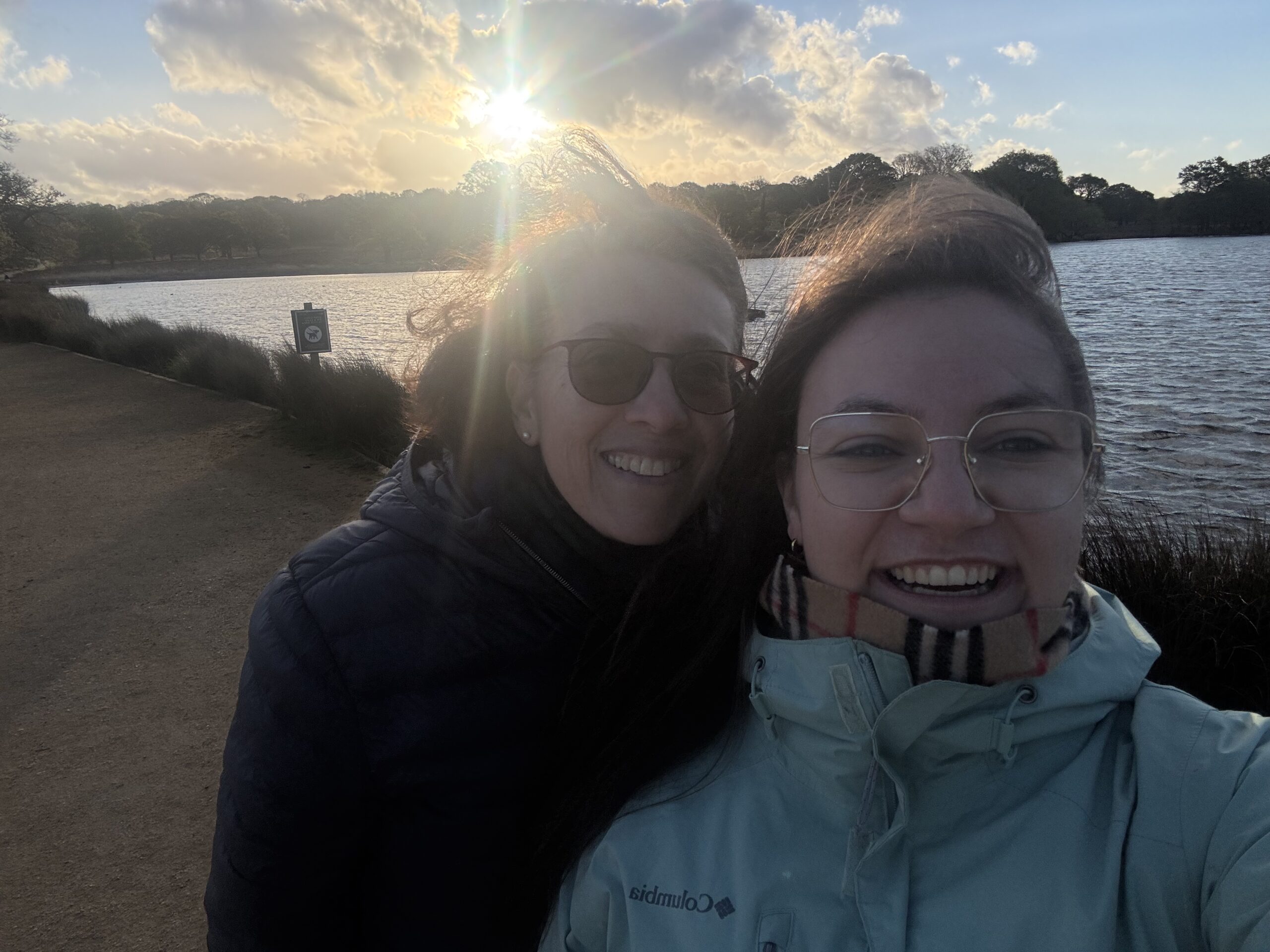 Zwei Frauen machen ein Selfie am See bei Sonnenuntergang